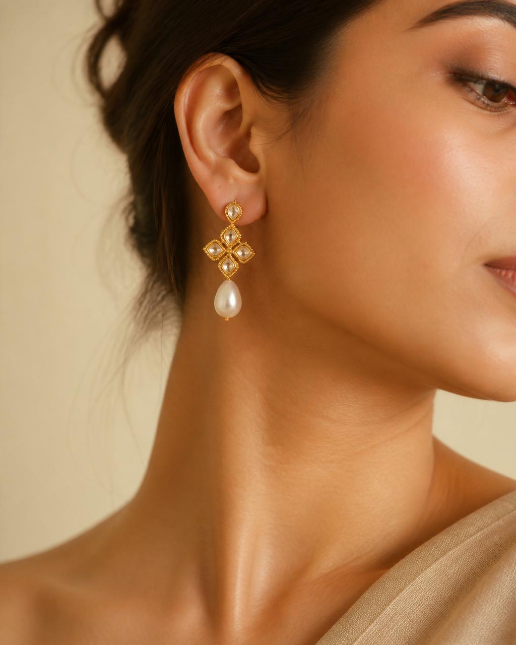 Close-up of a woman wearing a gold and pearl drop earring
