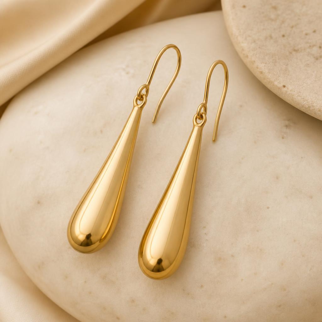 Elara Gold Drop Earrings photographed on a warm ivory background